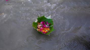 cuenco de hojas lleno de flores flotando en el lago. foto