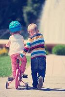 niño y niña en el parque aprendiendo a andar en bicicleta foto