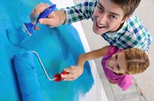 happy couple paint wall at new home photo