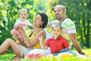 Feliz pareja joven con sus hijos divertirse en el parque foto