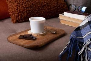 Autumn mood background with cup of cocoa, plaid and books on sofa. Hot drink in autumn concept photo