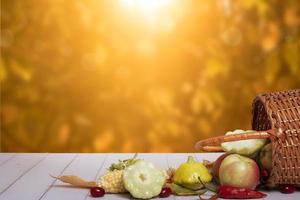 composición otoñal con una cesta de manzanas, calabazas, pimientos al fondo de un paisaje otoñal. concepto de cosecha de otoño foto