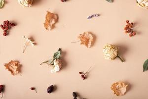 Autumn composition. Pattern made of dried leaves and flowers on pastel beige background. Autumn, fall concept. Flat lay, top view photo