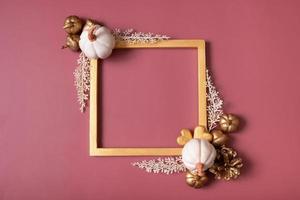Square golden frame blank with pumpkins and golden hearts on red background. Flat lay, top view, copy space photo