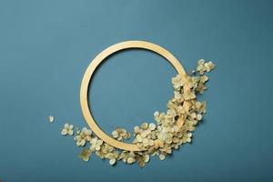 Golden ring and dried hydrangea flowers on a turquoise background. Flat lay, top view, copy space. photo