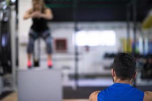 woman working out with personal trainer jumping on fit box photo