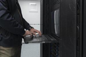 Close up on Data Center Engineer hands Using keyboard on a supercomputer Server Room Specialist Facility with Male System Administrator Working with Data Protection Network for Cyber Security. photo