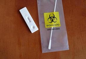 coronavirus - covid-19 - prueba rápida con resultado negativo junto a un hisopo nasal en una bolsa transparente con riesgo biológico