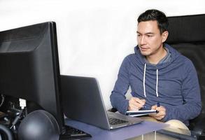 Man in casual outfit working from home with a laptop in the living room photo