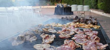 Smoking barbecue grill with numerous pieces of meat on it photo