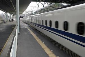 el shinkansen, el tren de alta velocidad japonés, pasa por una estación de tren en japón foto