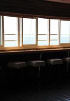 A row of bar stools in the dark with a view on the brightly lit ocean in a bar in Lebanon photo