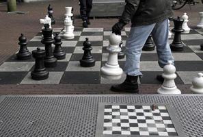 Small chess board next to a large one with two players competing photo