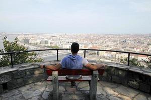 Man sitting on a bench with a view over the city of Budapest photo