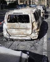 burned out gutted car wreck parked in residential street photo