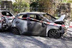 burnt out car wrecks behind police tape in residential street in Germany photo
