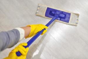 Girl in protective gloves cleaning floor using flat wet mop. photo