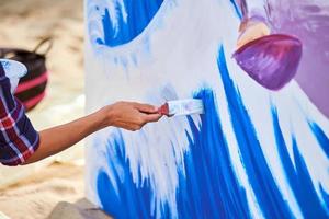 artista femenina trabajando en pintura acrílica abstracta, pincel de mano, lienzo grande al aire libre foto