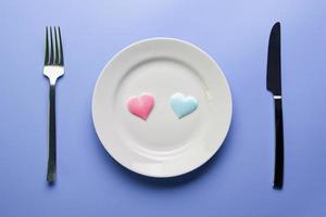 Two hearts in plate with cutlery. Romantic dinner in restaurant concept. Meeting of lovers at wedding reception. photo