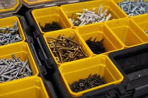 Yellow storage case with screws, nuts, bolts, nails and other small tools for handyman, close up photo