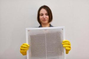 Woman holding dirty and dusty ventilation grille, disgusted photo