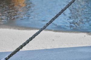 Rope on background of sea water in winter, close up photo