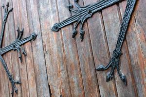 Forged pattern on door with decorative elements. Old vintage entrance, massive heavy wooden door of church or cathedral. photo