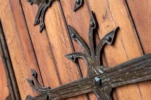 Forged pattern on door with decorative elements. Old vintage entrance, massive heavy wooden door of church or cathedral. photo