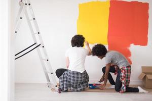 multiethnic couple painting interior wall photo