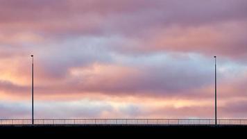 cielo rosa y violeta y siluetas de linternas en el puente foto