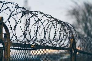 Barbed wire on fence of restricted area photo