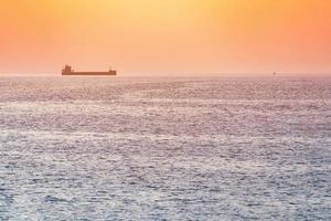 Little tugboat and big cargo ship. Beautiful sunset over sea. Breathtaking travel view, copy space. photo