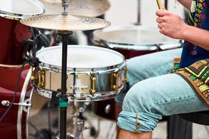 Drummer man playing drums percussion with sticks, drum kit on concert stage, drumsticks and drums photo