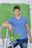 handsome young man paint white wall in color photo