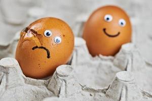 Funny egg and sad cracked egg in paper egg tray photo