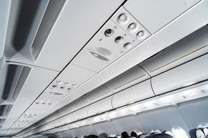 Airplane air conditioning control panel over seats. Stuffy air in aircraft cabin with people. New low-cost airline. photo