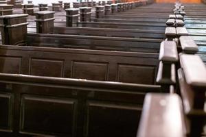 Cathedral benches. Rows of pews in christian church. Heavy solid uncomfortable wooden seats. photo
