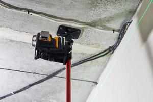 herramienta de medición de nivel láser con rayo láser verde visible en la pared para instalar techo tensado foto