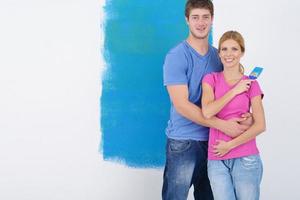 pareja feliz pintando una pared en su nuevo hogar foto