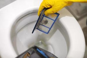 Hands in rubber gloves throw out trash in toilet, close up. photo