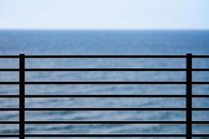 Fencing on observation deck, blue sea background, protection of tourists from falling off cliff photo