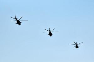 Military helicopters flying in blue sky performing demonstration flight, aerobatic team, air show photo