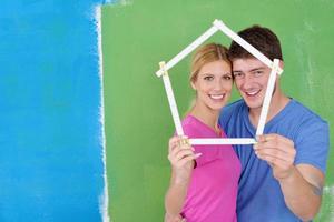 pareja feliz pintando una pared en su nuevo hogar foto