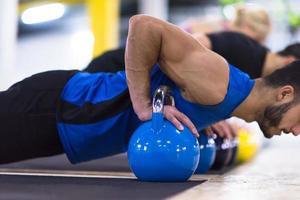 young athletes doing pushups with kettlebells photo