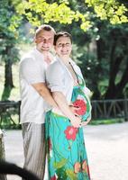 Happy pregnant couple at beautiful sunny day in park photo