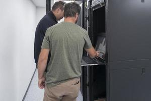 Technicians team updating hardware inspecting system performance in super computer server room or cryptocurrency mining farm. photo