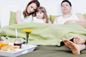 familia joven feliz desayunar en la cama foto