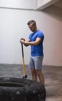 man workout with hammer and tractor tire photo