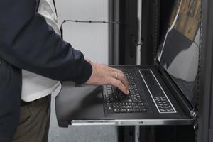 Close up on Data Center Engineer hands Using keyboard on a supercomputer Server Room Specialist Facility with Male System Administrator Working with Data Protection Network for Cyber Security. photo