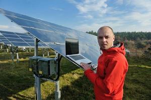 engineer using laptop at solar panels plant field photo